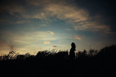 Silhouette of woman against sunset sky