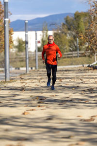 Senior man running on road during autumn