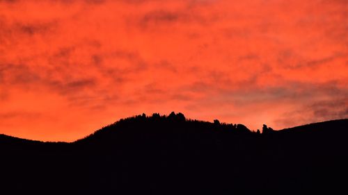 Low angle view of silhouette mountain against orange sky