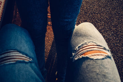 Close-up of person wearing torn jeans on road during sunset