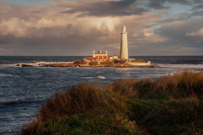 Lighthouse by sea against sky