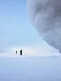 Two people on standing on snow covered field against sky