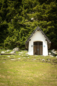 Built structure on field by trees in forest