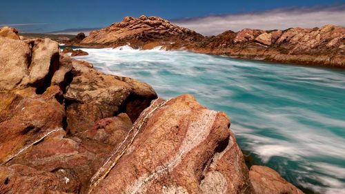 Rock formation on beach against sky