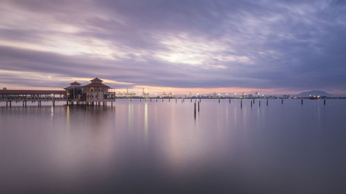 View of pier on water against cloudy sky