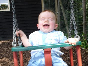 Cute boy playing on swing at playground