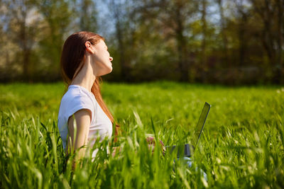 Side view of young woman standing on grassy field