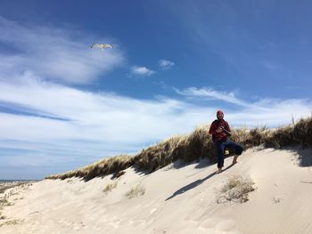 Man holding camera while standing on hill at beach