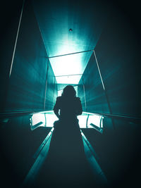 Rear view of silhouette woman standing on escalator