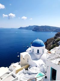 Buildings by sea against blue sky