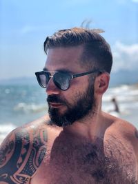 Close-up of shirtless man wearing sunglasses while standing at beach