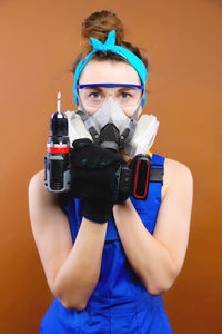 Portrait of man holding camera against gray background