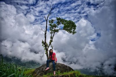 Person standing by tree against sky