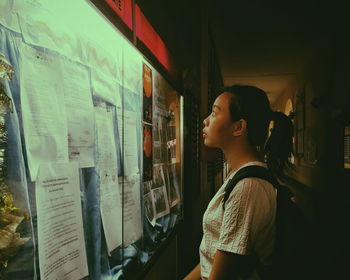 Woman reading notice while standing in college