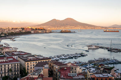 High angle view of townscape by sea against clear sky during sunset
