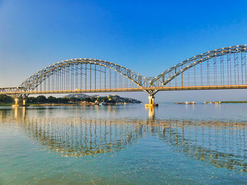 Bridge over river against clear blue sky