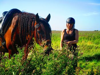 Woman with horse by plants against sky