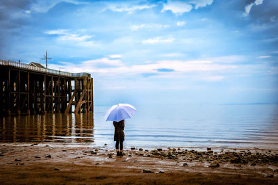 Woman with umbrella standing at beach
