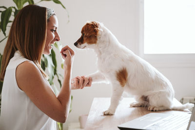 Side view of woman with dog sitting on table