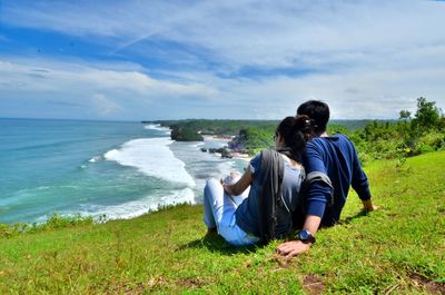 Rear view of woman sitting on beach