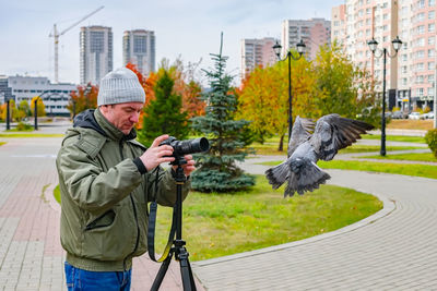 Photographer takes pictures of birds in the park in autumn