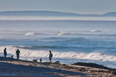 People on beach by sea against sky