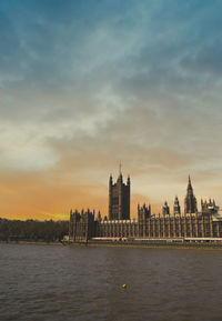 River by buildings against sky during sunset