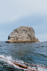 View of rock formation in sea against sky