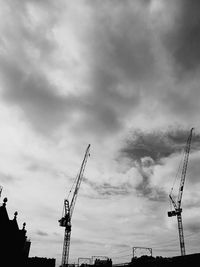 Low angle view of crane against cloudy sky