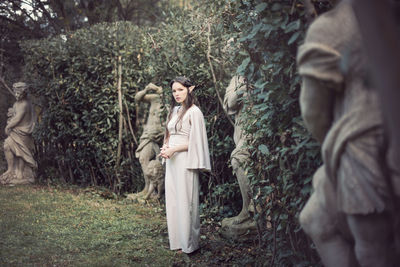 Portrait of woman standing by tree trunk in forest