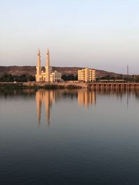 Reflection of building in lake against clear sky