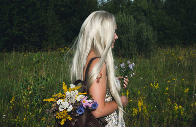 Woman standing by flowering plants on field