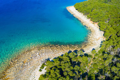 Aerial view of the rocky coast with the pebble beach and pine forest near pakostane in dalmacija