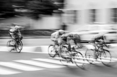 Blurred motion of people riding bicycle on road