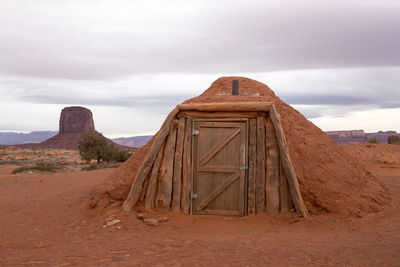 Traditional hogan made of red earth with wooden door in the monument valley navajo tribal park