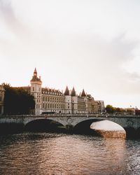 Arch bridge over river in city against sky