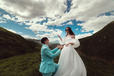 Rear view of couple standing on mountain against sky