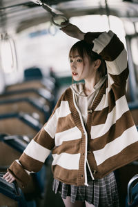 Portrait of young woman standing in bus