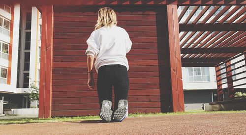 Rear view of woman standing against brick wall