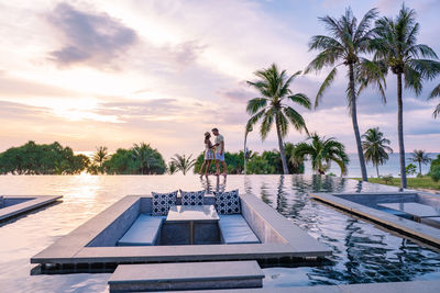 Couple embracing by pool at sunset