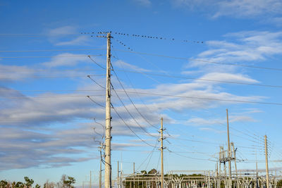 Low angle view of electricity pylon against blue sky