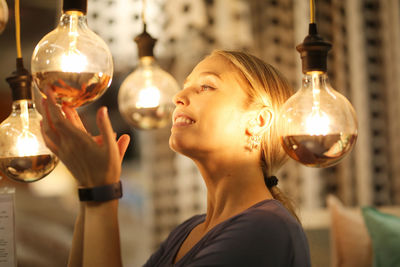 Side view of woman touching glowing light bulb