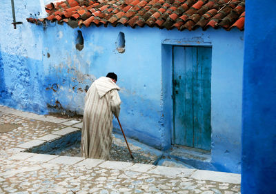 Rear view of man moving down on steps by house