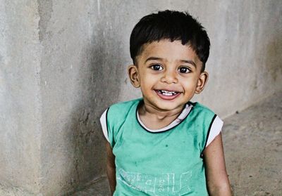 Portrait of smiling boy standing against wall