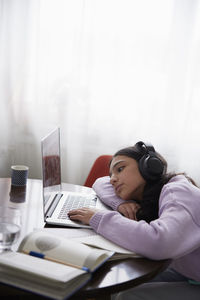 Girl doing homework with laptop at dining table