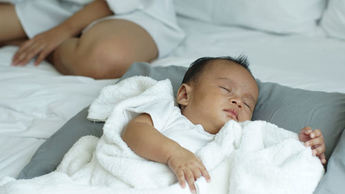 Close-up of cute baby boy sleeping on bed