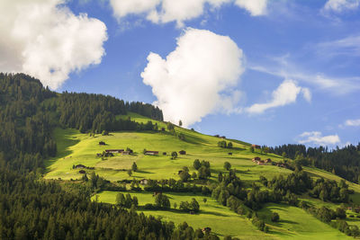 Green hill against cloudy sky