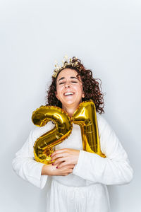 Smiling woman wearing hat holding balloons against white backgrounds