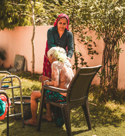 Daughter bathing her old mother in the yard