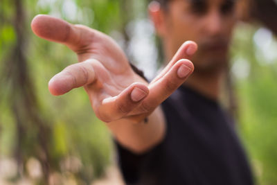 Close-up of man gesturing against trees